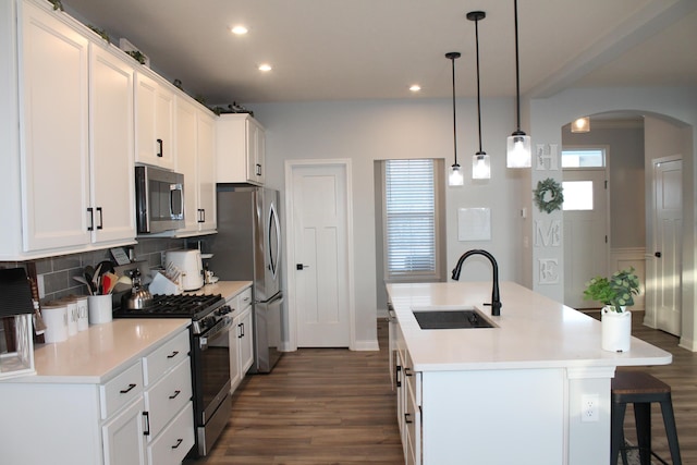 kitchen featuring a center island with sink, stainless steel appliances, light countertops, white cabinetry, and a sink