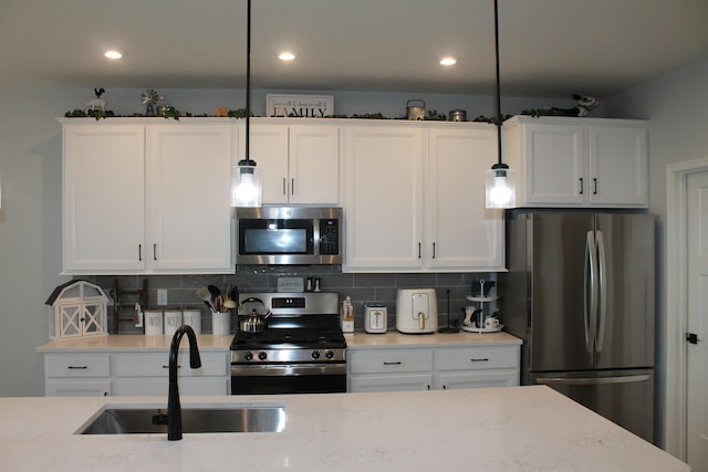 kitchen featuring stainless steel appliances, pendant lighting, white cabinets, and a sink