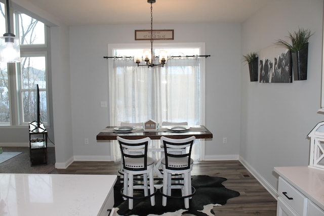 dining area with a chandelier, dark wood-type flooring, and baseboards