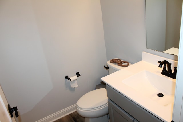 bathroom with baseboards, vanity, and toilet