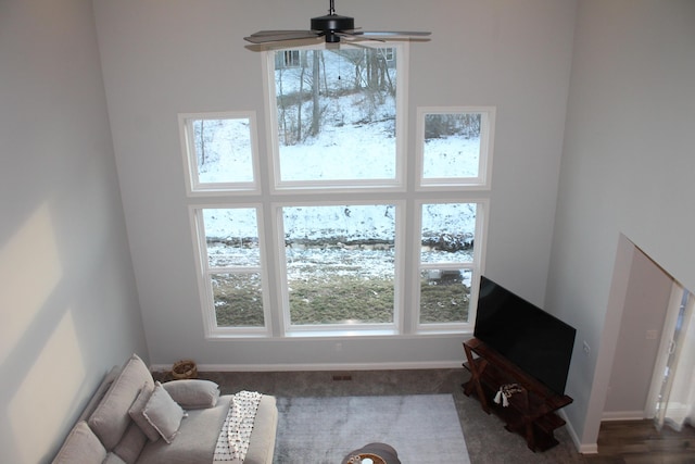 living area with a ceiling fan and baseboards