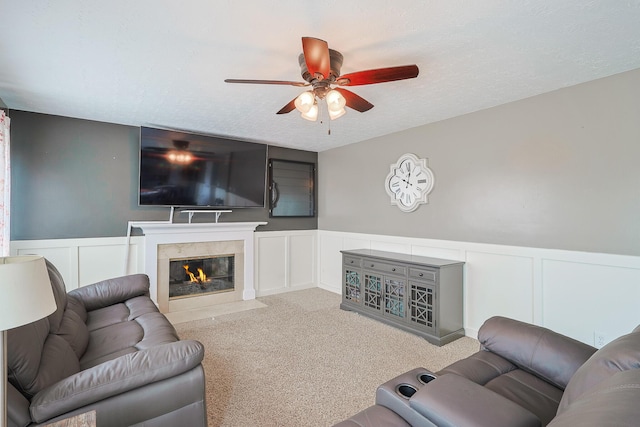 living room featuring wainscoting, carpet flooring, a textured ceiling, and a premium fireplace