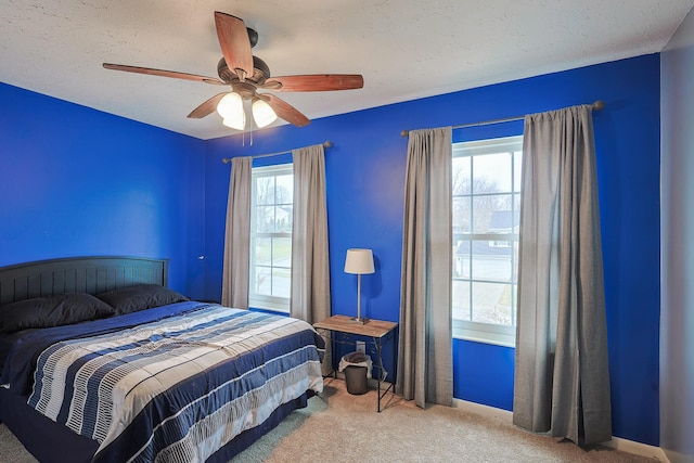 carpeted bedroom featuring ceiling fan and a textured ceiling