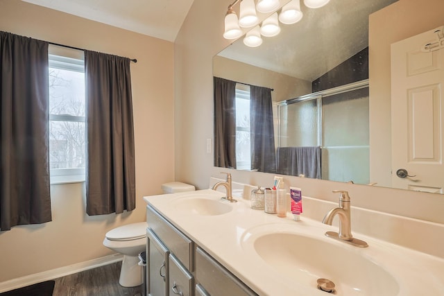 bathroom featuring a sink, a shower stall, toilet, and double vanity