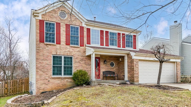 traditional-style home with a garage, driveway, brick siding, and fence