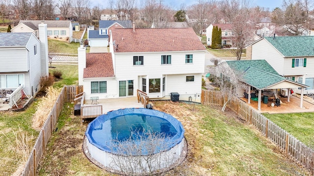 back of property with a fenced backyard, a residential view, roof with shingles, and a wooden deck