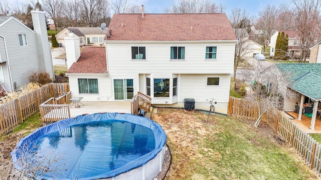 rear view of property with a fenced backyard, a deck, a fenced in pool, and roof with shingles