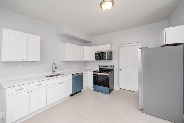 kitchen with light tile patterned floors, stainless steel appliances, a sink, white cabinets, and light countertops