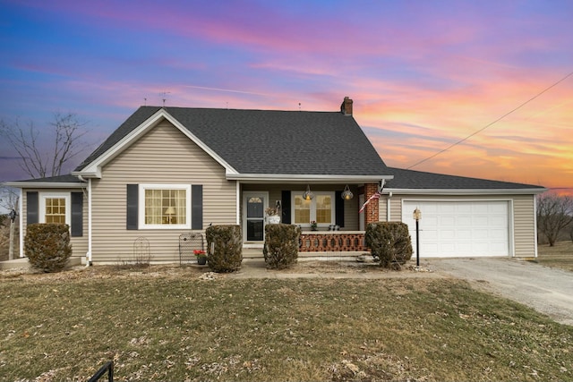 view of front of house featuring a garage, covered porch, a yard, and driveway