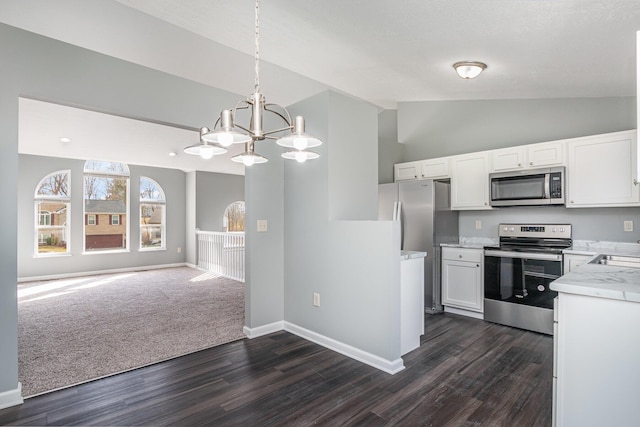 kitchen featuring white cabinetry, open floor plan, light countertops, appliances with stainless steel finishes, and vaulted ceiling