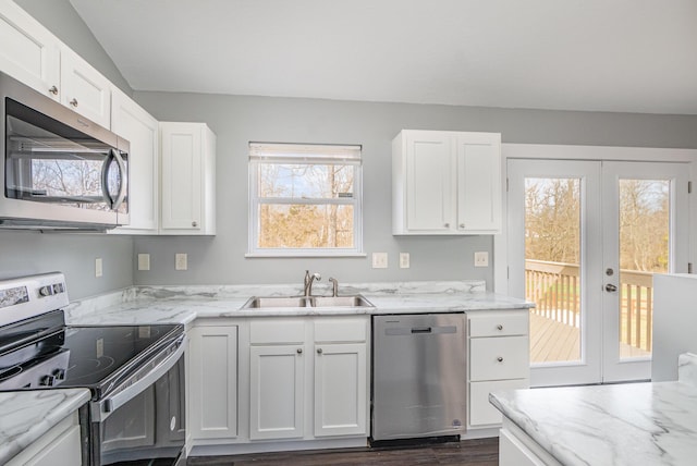 kitchen with light stone countertops, white cabinetry, appliances with stainless steel finishes, and a sink