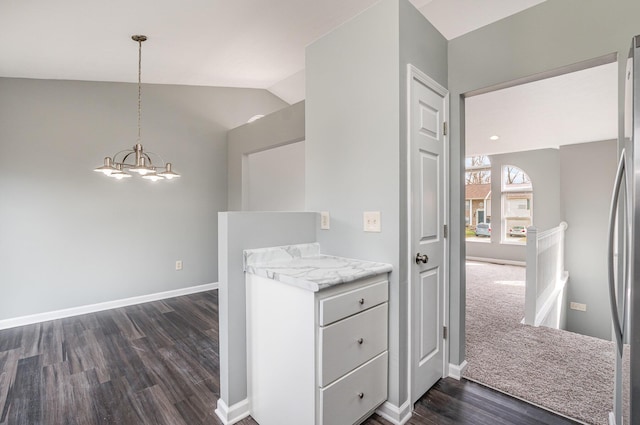 kitchen featuring lofted ceiling, a notable chandelier, dark wood-type flooring, baseboards, and hanging light fixtures