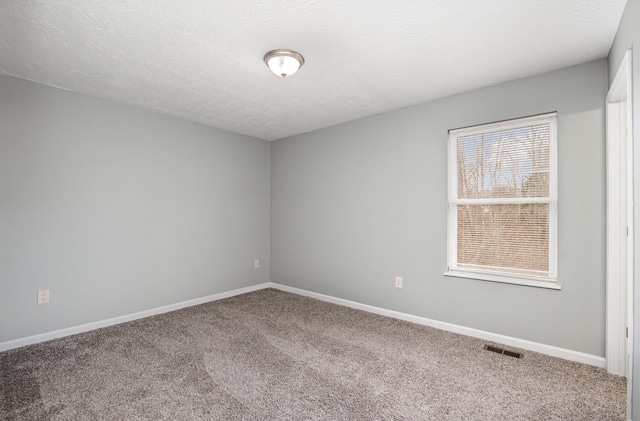 carpeted spare room featuring baseboards, visible vents, and a textured ceiling