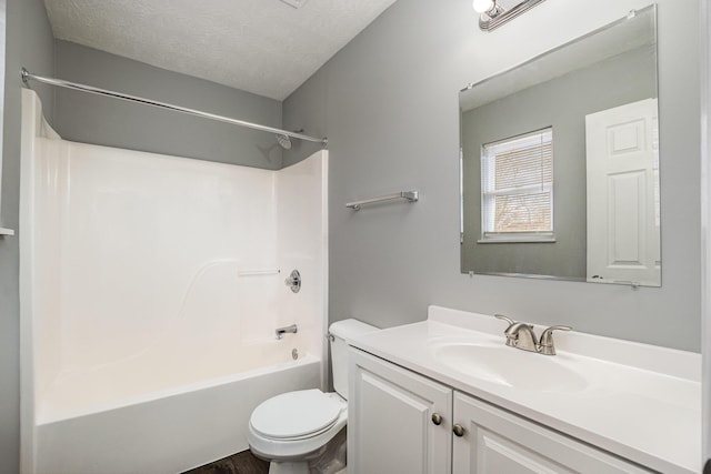 bathroom with a textured ceiling, shower / bathing tub combination, toilet, and vanity