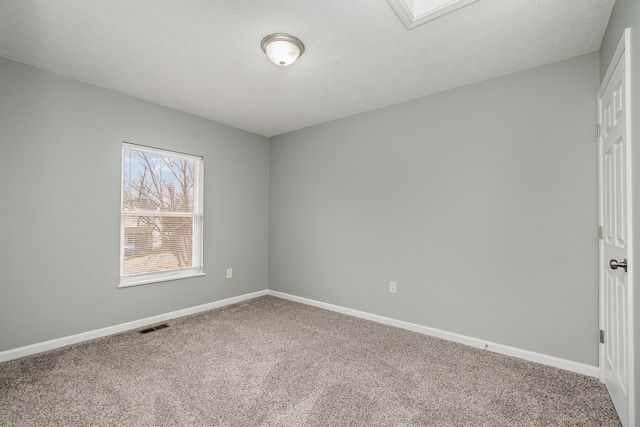 spare room featuring carpet, visible vents, and baseboards