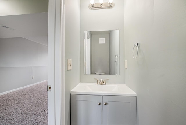 half bathroom featuring lofted ceiling, baseboards, and vanity