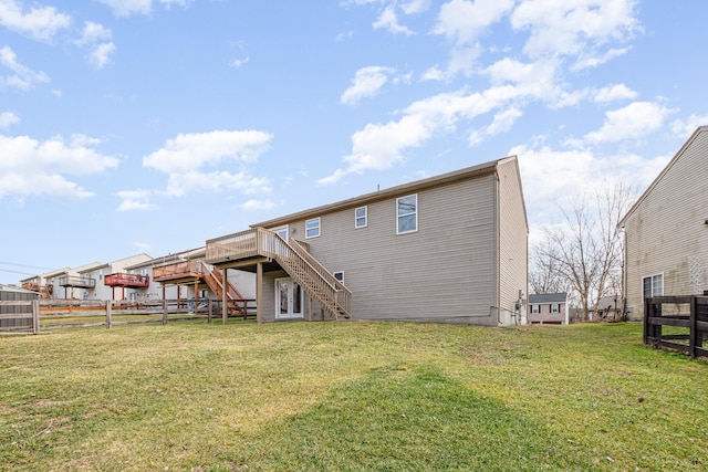 back of property with a deck, a lawn, stairway, and fence