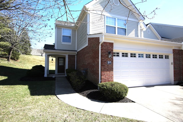 traditional-style home with a garage, a front yard, concrete driveway, and brick siding