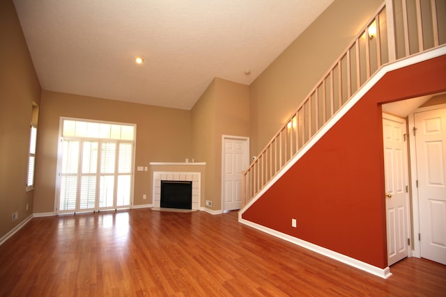 unfurnished living room featuring stairs, a fireplace, baseboards, and wood finished floors