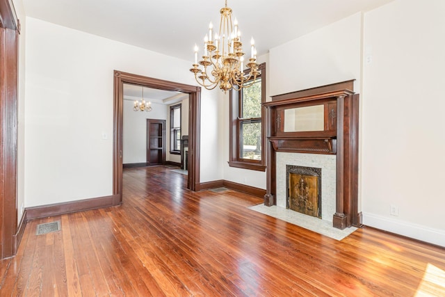 unfurnished living room with visible vents, a fireplace with flush hearth, hardwood / wood-style flooring, and baseboards