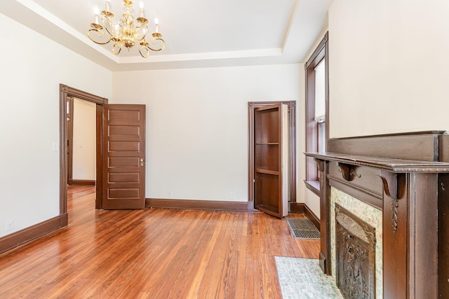 unfurnished living room with a tray ceiling, baseboards, and wood finished floors