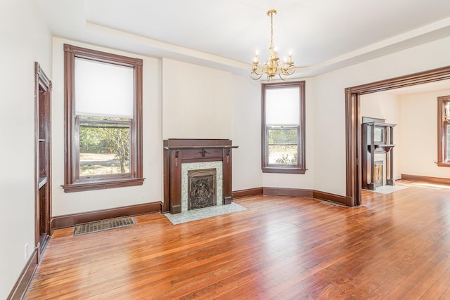 unfurnished living room featuring light wood-type flooring, a tray ceiling, a fireplace, and visible vents