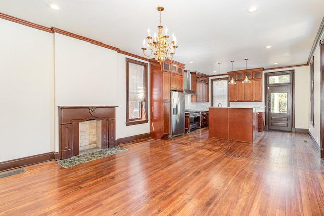 kitchen with stainless steel appliances, visible vents, wall chimney exhaust hood, brown cabinetry, and crown molding