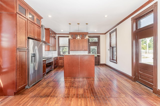 kitchen with tasteful backsplash, wall chimney exhaust hood, appliances with stainless steel finishes, and brown cabinetry