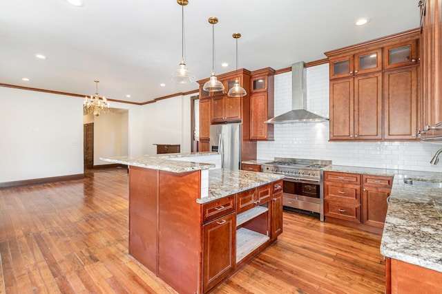 kitchen with wall chimney range hood, light wood-style floors, stainless steel appliances, and a sink