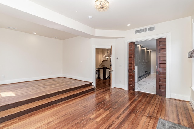 unfurnished room with recessed lighting, visible vents, hardwood / wood-style floors, and baseboards