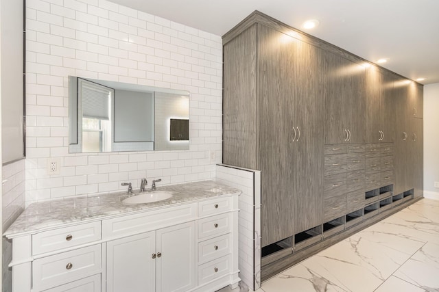 bathroom featuring marble finish floor, recessed lighting, vanity, and tile walls