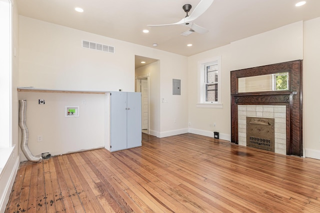 unfurnished living room with a tile fireplace, recessed lighting, visible vents, light wood-type flooring, and electric panel