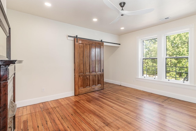 interior space with a barn door, baseboards, a ceiling fan, light wood-style flooring, and recessed lighting