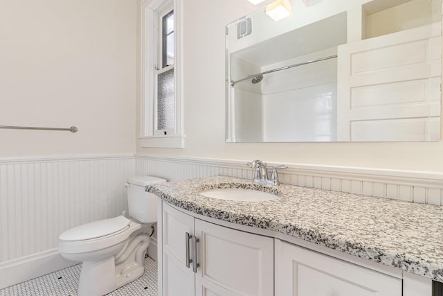 bathroom with wainscoting, vanity, toilet, and tile patterned floors