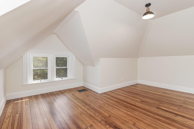 additional living space featuring lofted ceiling, wood-type flooring, visible vents, and baseboards