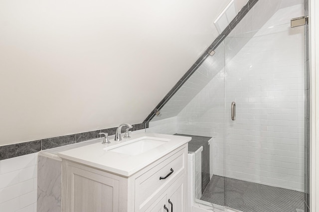 full bathroom with tile walls, vaulted ceiling, a shower stall, and vanity