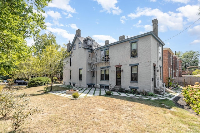 rear view of house with entry steps, brick siding, a lawn, and a chimney