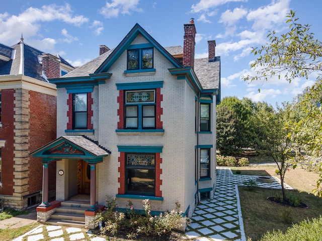 view of front of home featuring a chimney and brick siding