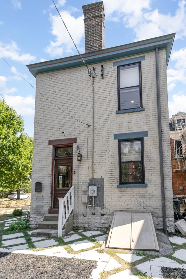 rear view of property featuring brick siding and a chimney