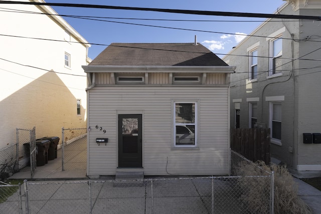 rear view of house with roof with shingles and fence