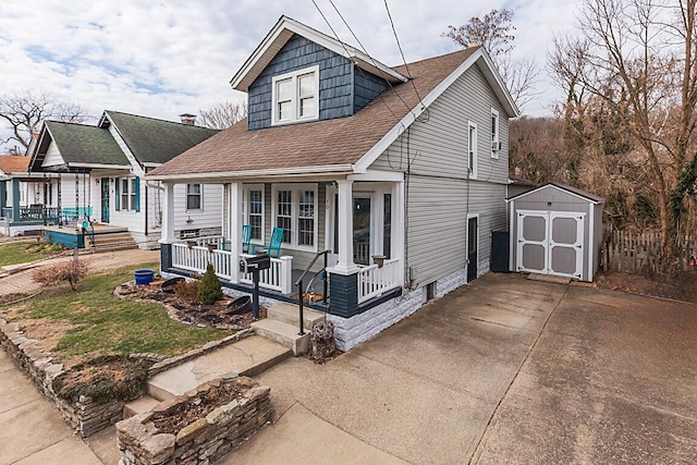 bungalow-style house featuring driveway, a storage shed, a shingled roof, an outbuilding, and a porch