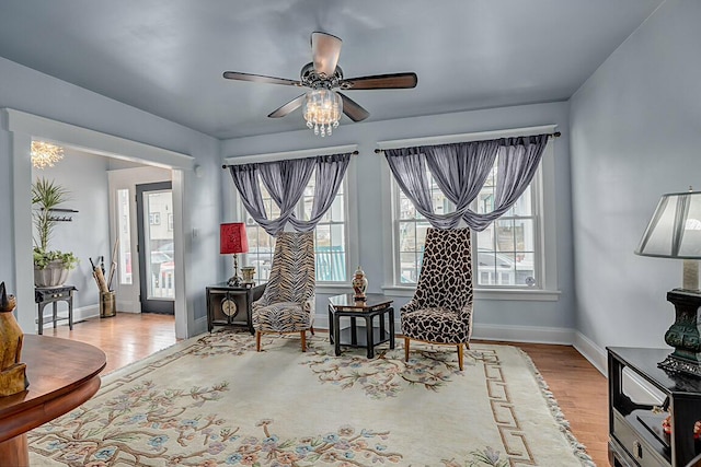 living area featuring baseboards, a ceiling fan, and wood finished floors