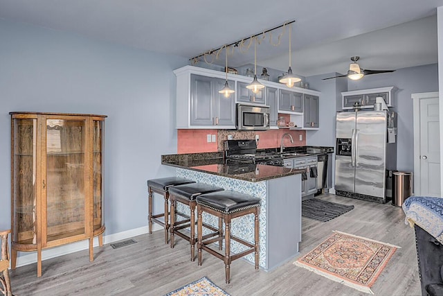 kitchen with visible vents, decorative backsplash, appliances with stainless steel finishes, a peninsula, and light wood-type flooring