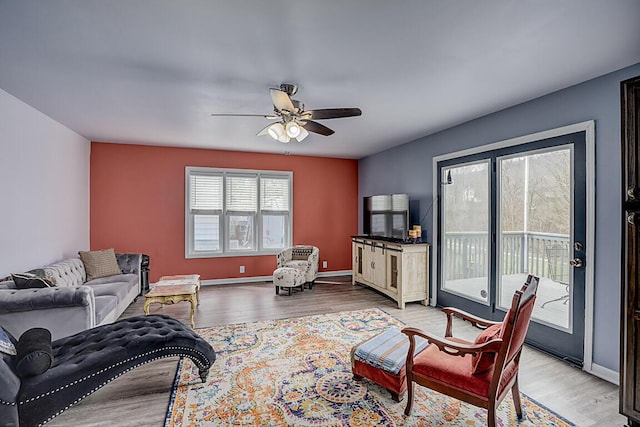 living area with baseboards, a ceiling fan, and wood finished floors