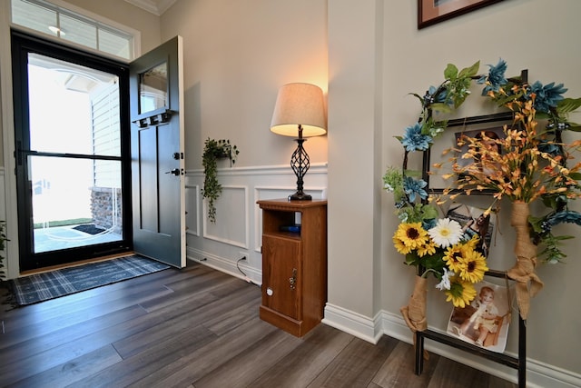 foyer with dark wood-style floors, wainscoting, and a decorative wall