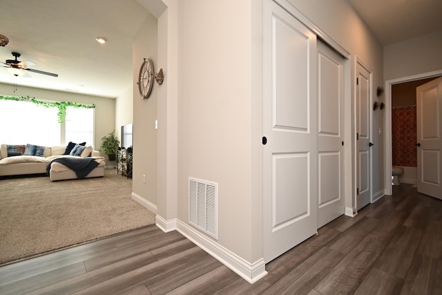 hall with baseboards, visible vents, arched walkways, and dark wood-type flooring