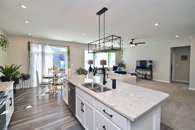 kitchen with a center island with sink, hanging light fixtures, stainless steel dishwasher, white cabinets, and a sink