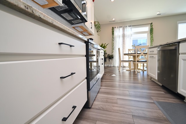 kitchen with white cabinets, dishwasher, and wood finished floors