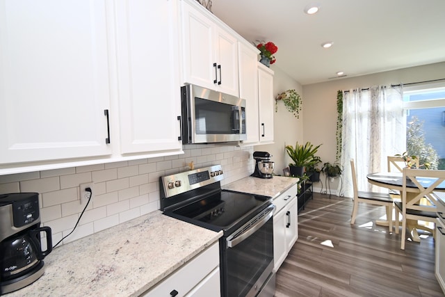 kitchen with stainless steel appliances, dark wood-style flooring, white cabinets, backsplash, and light stone countertops