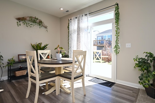 dining area featuring baseboards, dark wood-type flooring, visible vents, and a healthy amount of sunlight